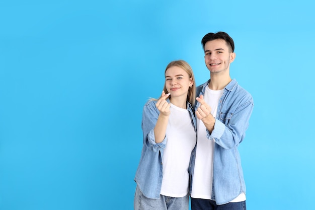 Cute couple with finger hearts on blue background