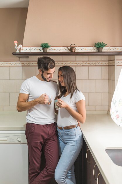 Cute couple with mugs on stylish kitchen