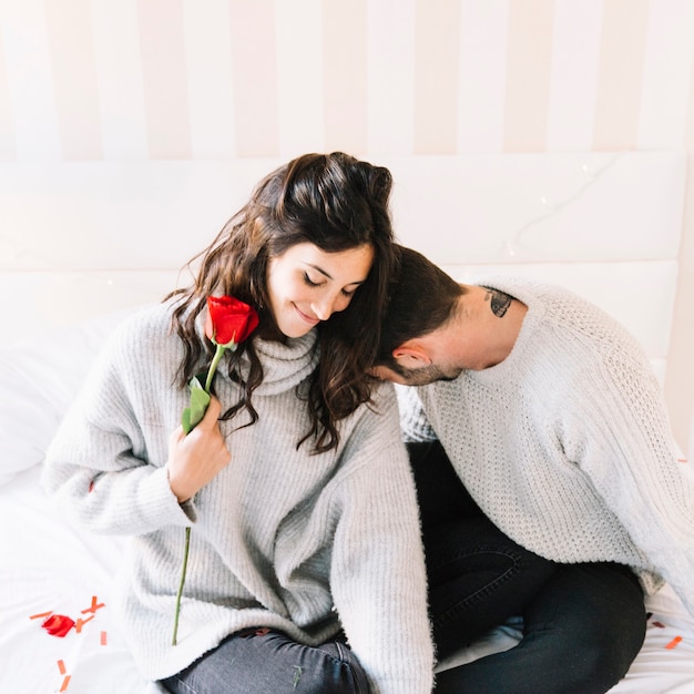 Free photo cute couple with rose sitting on bed