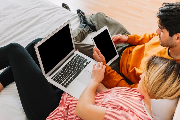 かわいいカップル、タブレットとラップトップ