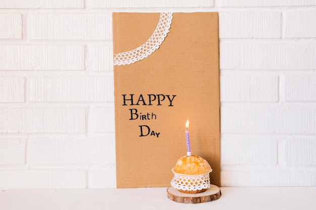 Free photo cute cupcake near cardboard with birthday greeting