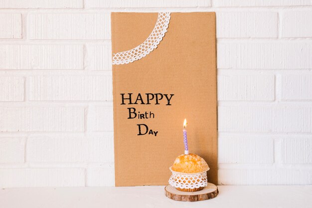 誕生日のあいさつのあるボール紙の近くのかわいいカップケーキ