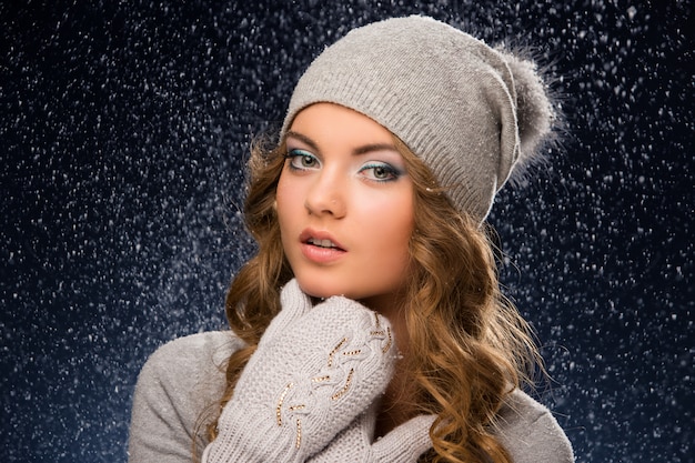 Cute curly girl wearing mittens during snowfall