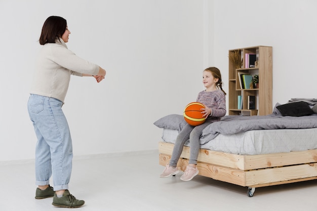 Милая дочь держит баскетбол в помещении