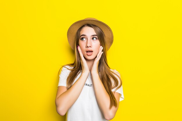 Cute embarrassed model in white t-shirt and hat among orange background with funny face