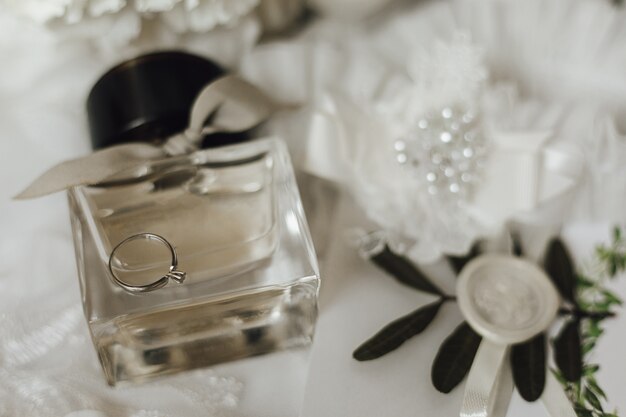 Cute engagement ring made of white gold with diamond on the glass bottle of perfume