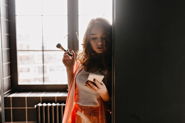 Cute european girl doing makeup in bathroom Sensual curly woman posing at home early in morning