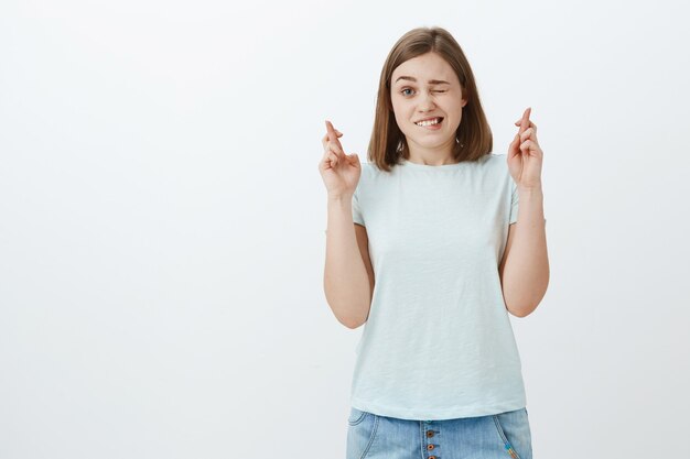 cute excited and hopeful female fan watching important game peeking with one eye and crossing fingers for good luck feeling nervous observing important game of favorite team