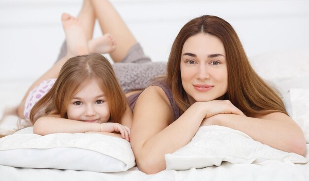 cute family mother and daughter on pillows