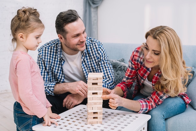 Cute family playing wooden block game tower at home