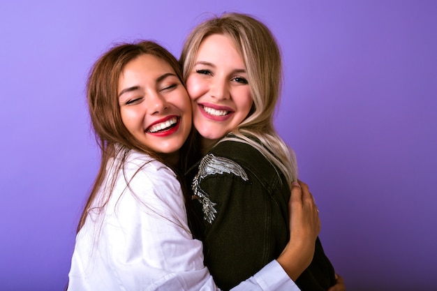 Free photo cute family portrait of two sister womanâs hugs and smile, lifestyle studying portrait, trendy hipster outfits, relations concept, natural beauty, happy together.