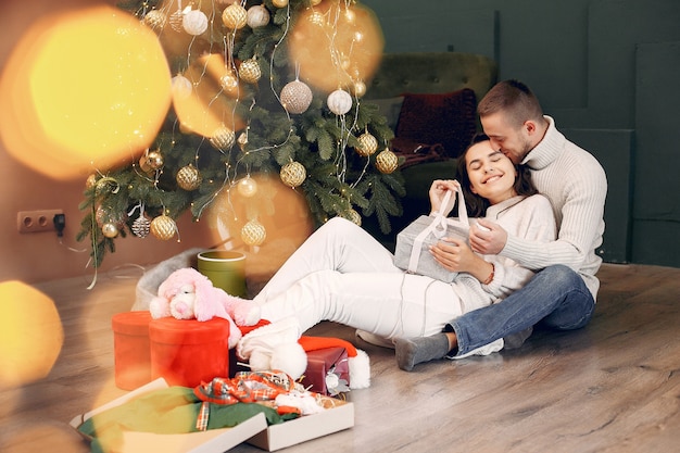 Famiglia sveglia che si siede a casa vicino all'albero di natale