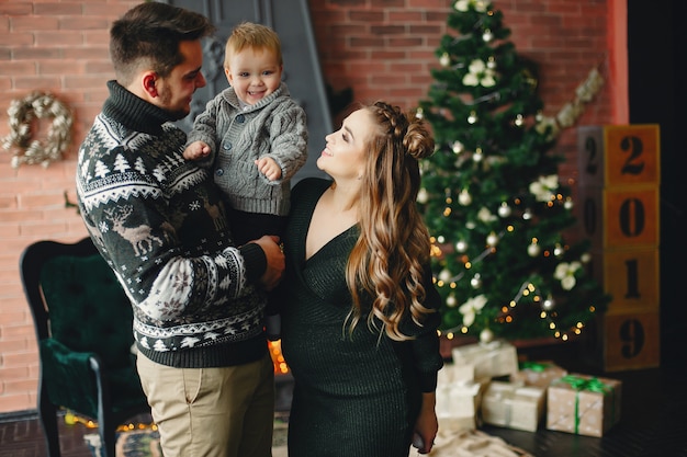 Cute family sitting near Christmas tree