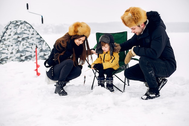 Cute family sitting on a winter fishing with little son