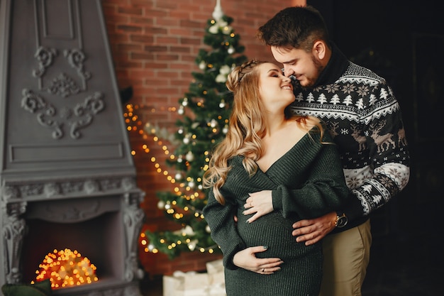 Famiglia sveglia che si leva in piedi vicino all'albero di natale