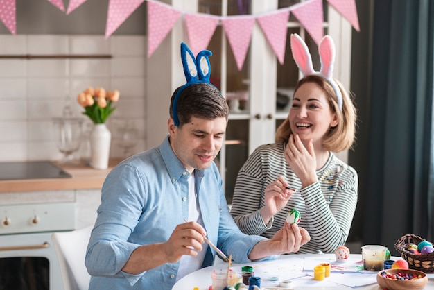 Cute father and mother painting traditional easter eggs