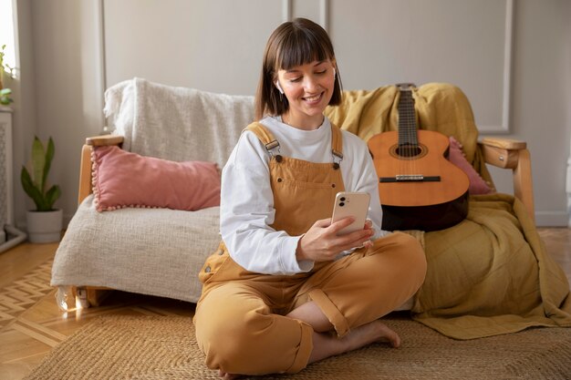 彼女の携帯電話をチェックするかわいい女性ギタリスト