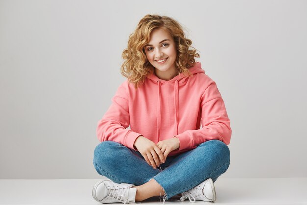 Cute female student sitting on floor with crossed feet