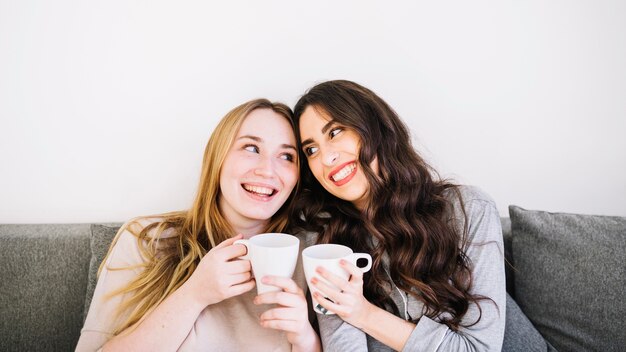 Cute friends drinking on couch