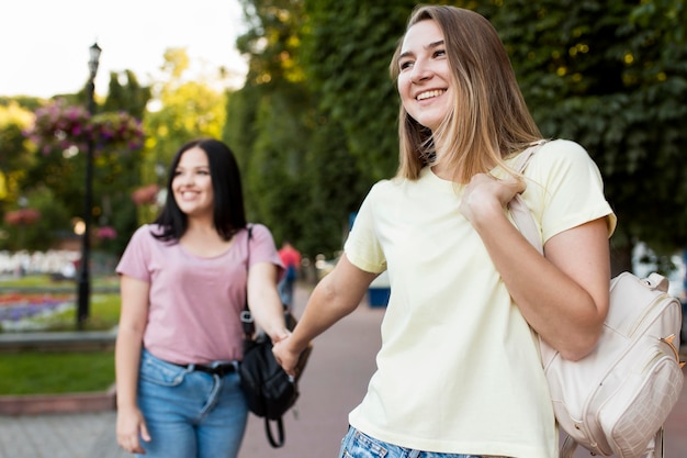 Cute friends holding hands outdoors