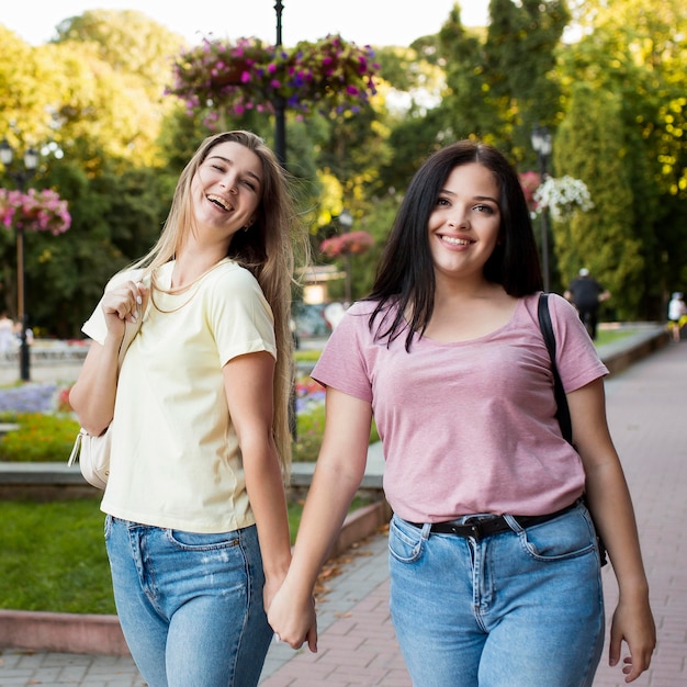 Cute friends holding hands outside