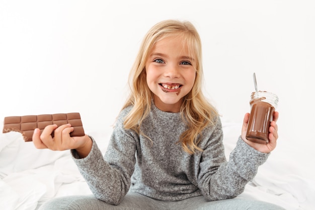 Barra di cioccolato divertente sveglia della tenuta della ragazza e mostrarle i denti sporchi