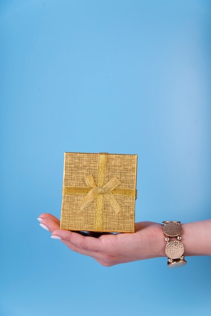 Free photo cute gift box held in hand on blue background