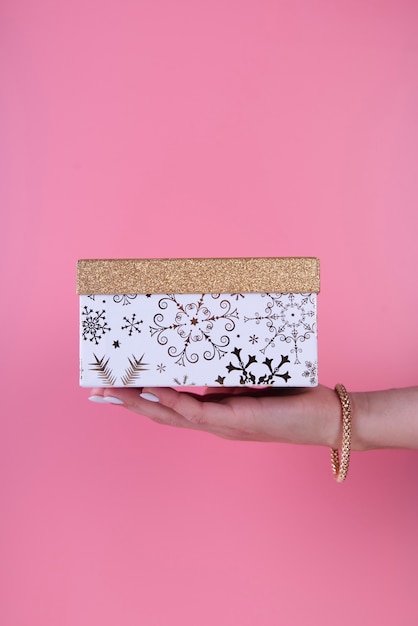 Бесплатное фото Симпатичная подарочная коробка в руке на розовом фоне