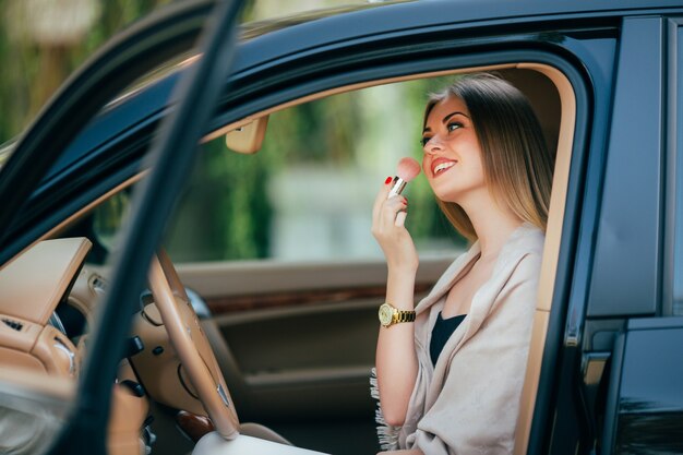 Cute  girl applying lipstick in a car