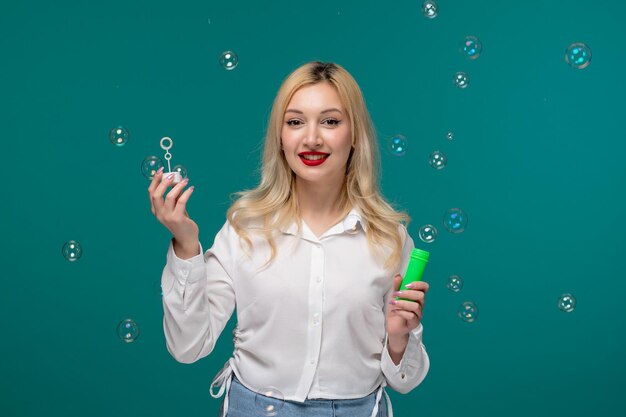 Cute girl blonde beautiful young girl in a white neat shirt with soap bubbles