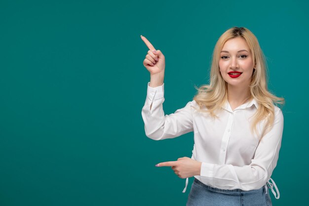 Cute girl blonde young pretty girl in a white shirt pointing fingers and smiling cute