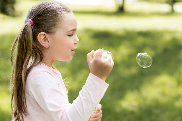Милая девушка дует пузыри со своей игрушкой