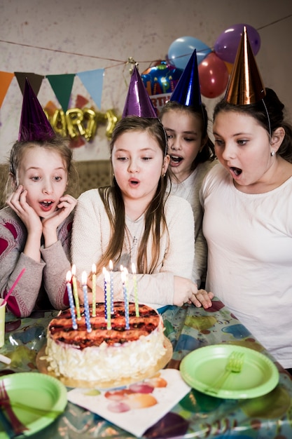 Free photo cute girl blowing candles on cake