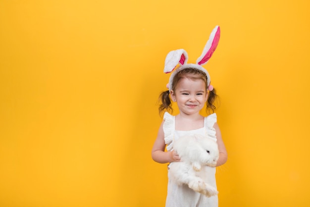 Cute girl in bunny ears standing with rabbit 