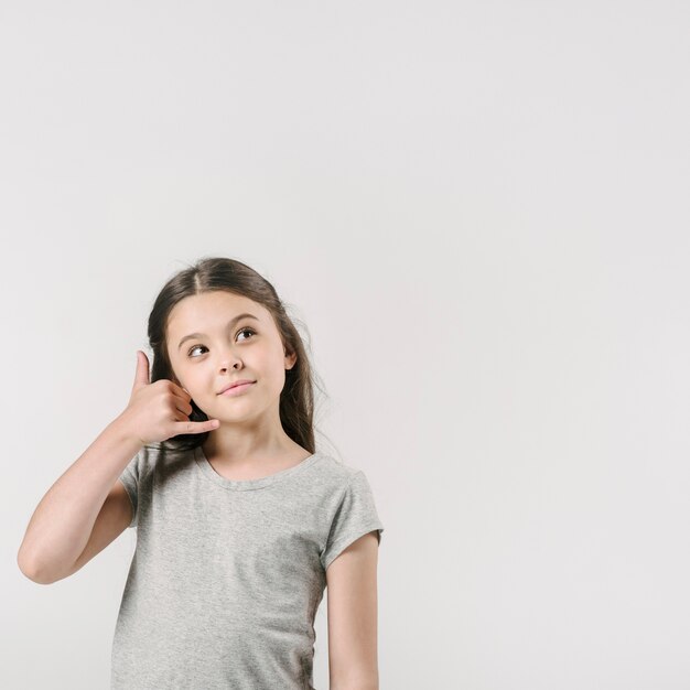 Cute girl calling with hand in studio