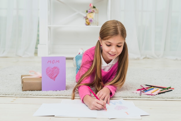 Бесплатное фото Милая девушка, рисунок на бумаге возле поздравительной открытки