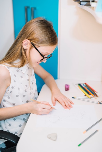 Foto gratuita disegno sveglio della ragazza con la matita al tavolo luminoso