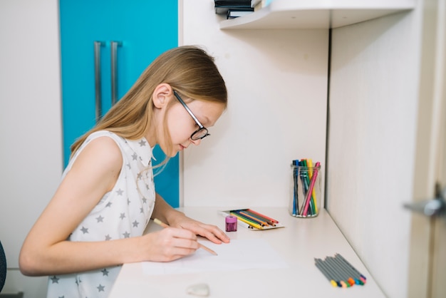 Free photo cute girl drawing with pencil at table