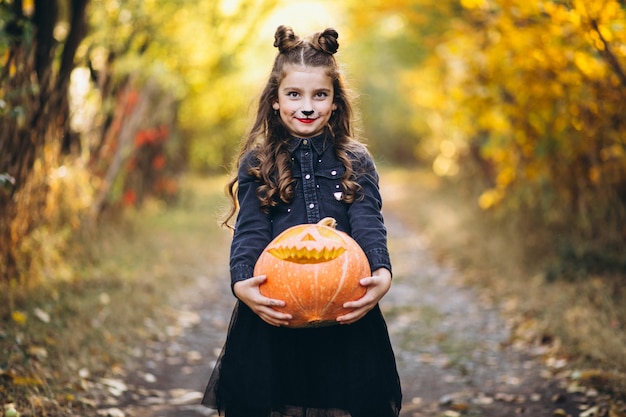 Free photo cute girl dressed in halloween costume outdoors with pumpkins