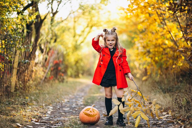 Cute girl dressed in halloween costume outdoors with pumpkins