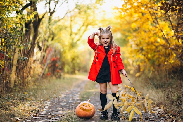 Cute girl dressed in halloween costume outdoors with pumpkins