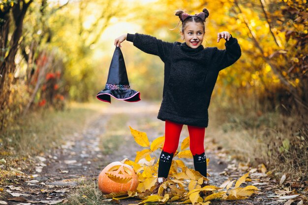 Милая девушка, одетая в костюм Хэллоуина на открытом воздухе с тыквами