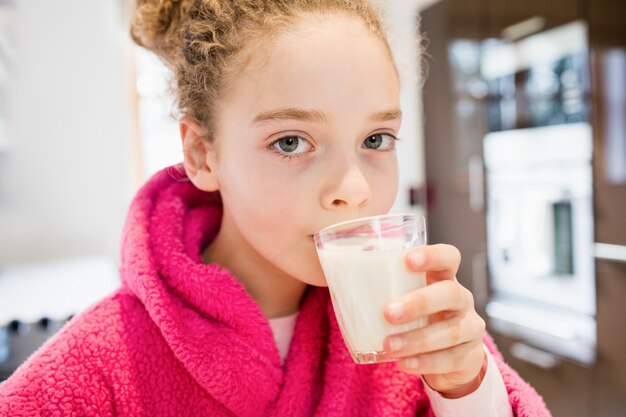 Cute girl drinking milk in kitchen