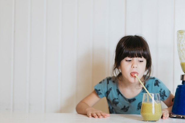 Cute girl drinking smoothie with straw