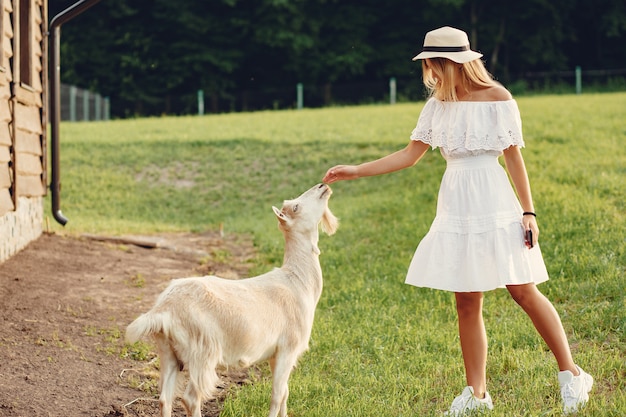 Foto gratuita ragazza sveglia in un campo con capre