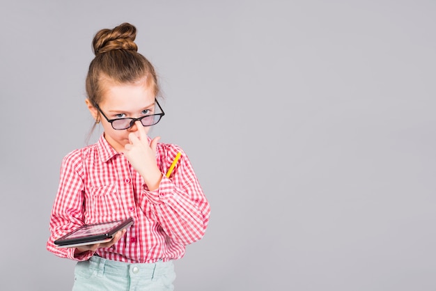 Free photo cute girl in glasses standing with tablet