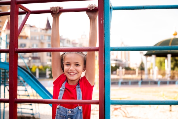 Cute girl hanging on a bar while looking at camera