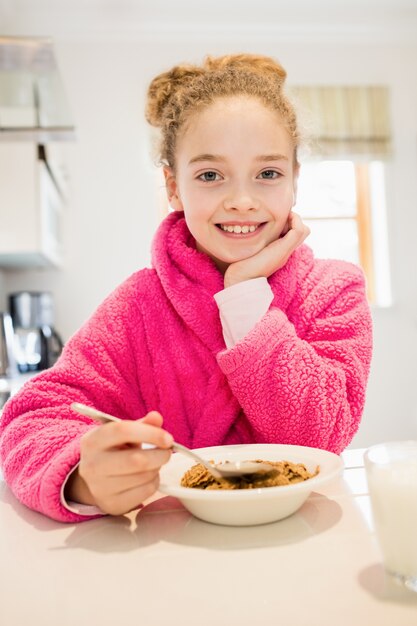 Cute girl having breakfast in kitchen