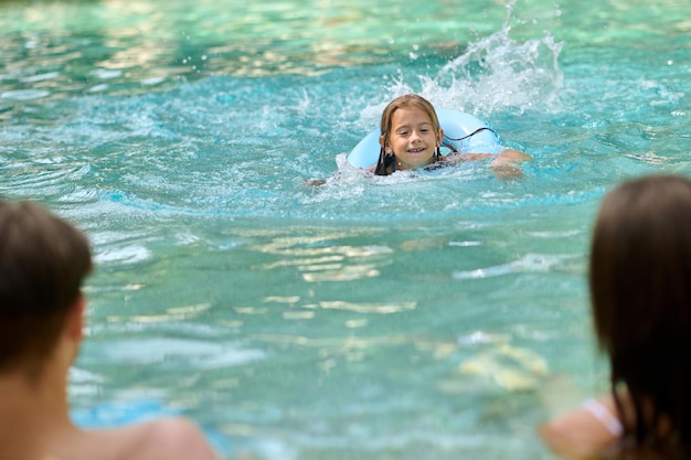 Cute girl and her parents spending time at the swimming pool