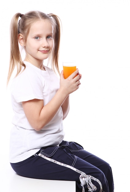 新鮮なオレンジジュースのガラスを保持しているかわいい女の子